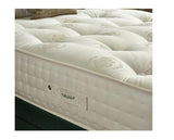 A close-up of a tufted mattress corner showing the white quilted top, a side label reading nature+, and part of a dark green mattress base.