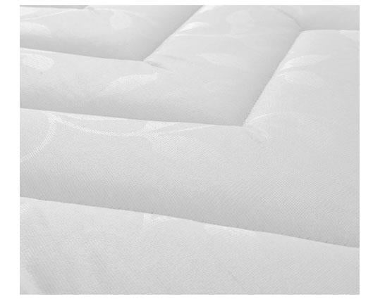 A close-up of a white quilted mattress  surface with subtle tonal leaf-like patterns in the fabric.