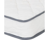 A close-up of a white quilted mattress topper or mattress corner with gray piping trim along the edges.