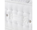 Close-up of a white quilted mattress or cushion with tufted texture, a central fabric strap, and two metal rivets on a white background.