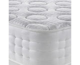 A close-up of a white tufted mattress showing the quilted top surface with circular button tufts and the padded side bolster.