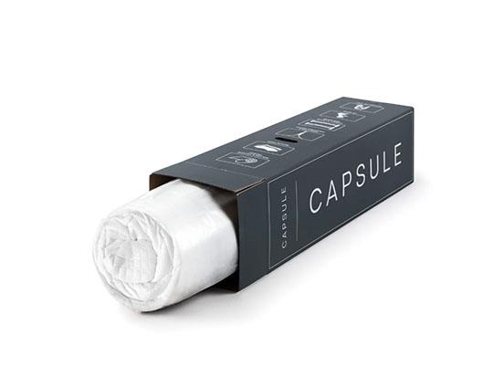 A black capsule packaging box with a white rolled capsule partially pulled out, shown on a clean white background.