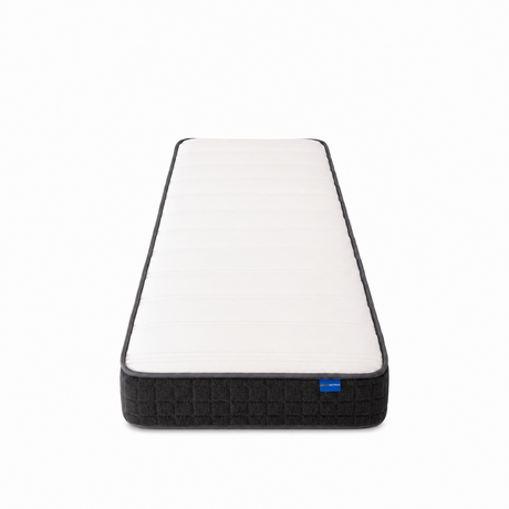 A single mattress shown from a top-down perspective on a clean white background. The mattress features a white quilted top surface with a dark gray or black textured base and a small blue brand tag on the right side.
