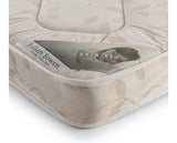 A close-up of a mattress corner showing a beige fabric cover with a subtle leaf pattern and a paper label that reads 'Julian Bowen' and 'CABIN BED'.