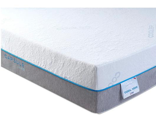 A white and gray mattress shown at an angle on a white background, featuring a blue trim line, a side label reading 'COOL-1000', and 'CAPSULE' branding on the side.