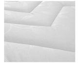 A close-up of a white quilted  mattress surface with subtle tonal leaf-like patterns in the fabric.