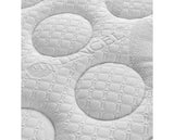 Close-up of a white quilted mattress topper with circular tufted patterns and a subtle leaf motif.